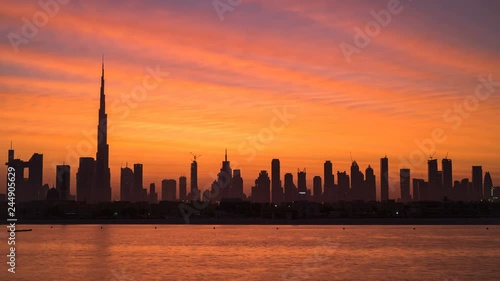 Sunrise in Dubai timelapse, dawn over Burj Khalifa. New day in Dubai under sun, beautiful colored cloudy sky over downtown from night to morning. Solar path on sea comes from Burj Khalifa. Jan 2019