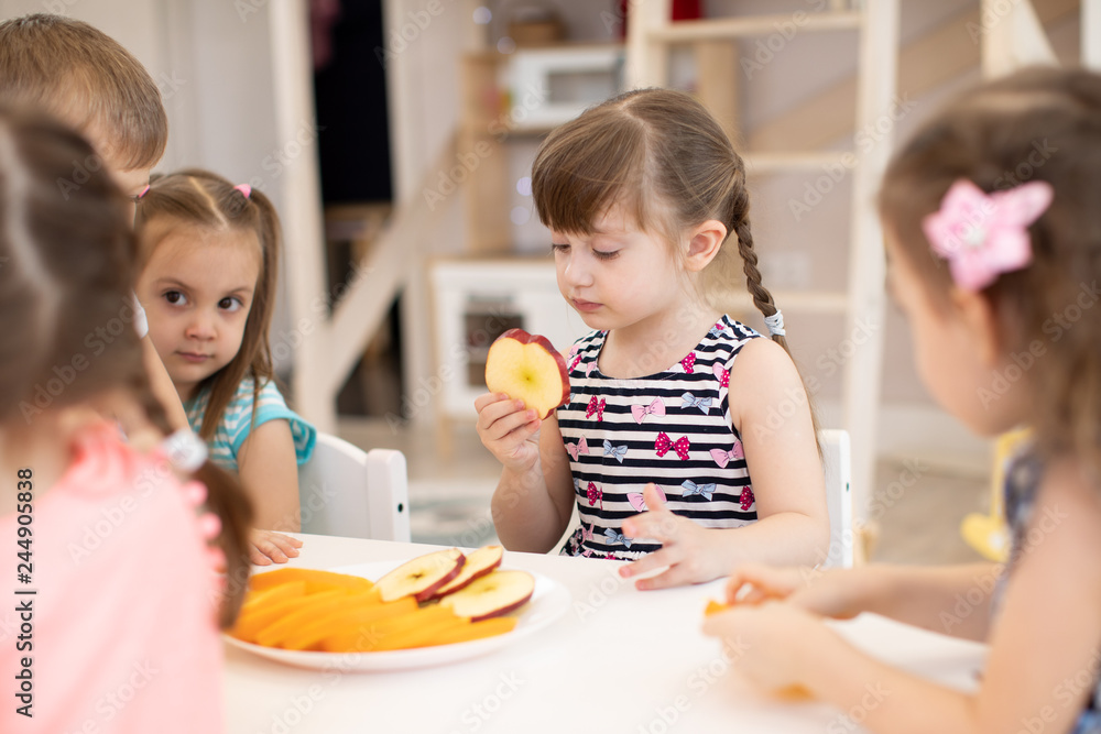 Group of kids have a lunch in daycare centre. Children eating fresh fruits in kindergarten Group of kids have a lunch in daycare centre. Children eating fresh fruits in kindergarten