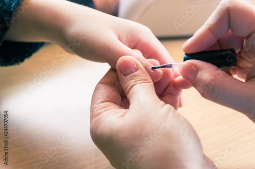 Polishing fingernails of young girl