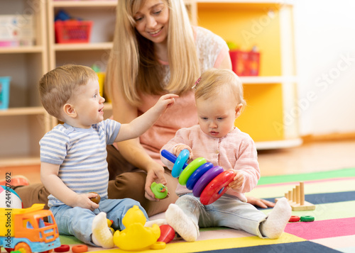 cute babies play with carer in nursery or kindergarten
