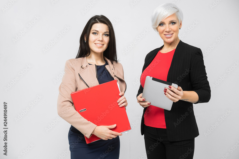 Portrait of two ladies with document folder and tablet in hand isolated on white background Portrait of two ladies with document folder and tablet in hand isolated on white background