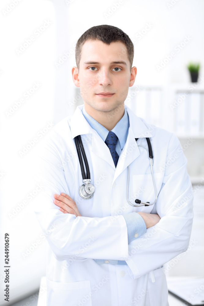 Smiling doctor waiting for his team while standing upright Smiling doctor waiting for his team while standing upright