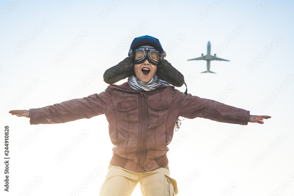 Handsome boy plays happily race with airplane joyfully pretending to take  off disguised as a vintage aviation pilot hat, glasses mask leather jacket  and fluttering foulard Concept image of kids dreams Stock