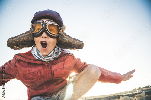 Fotografia Handsome blond boy plays happy and joyful pretending to take off his flight disg