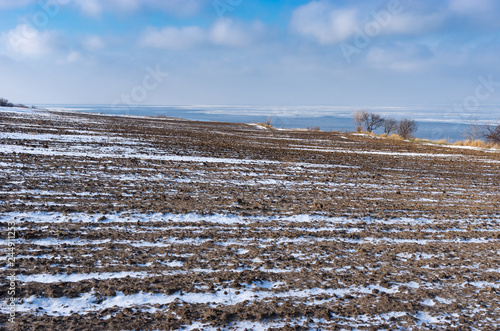 Winter landscape with ploughed fields near Kakhovka Reservoir on the Dnipro River, Skelki village, Ukraine. photo