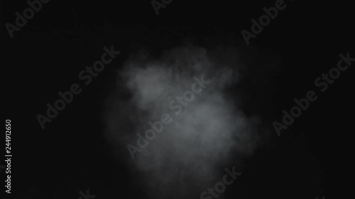 Dusty bullet hit on a wall with chunks of debris flying out. White powder explosion on black background.Impact  dust particles. Dust explosion in front of black background, slow-motion close up.