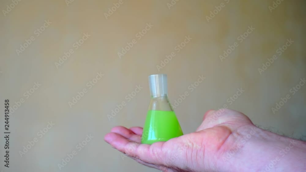 hand holding a flask with bright liquid.closeup hand holding a flask with bright liquid.closeup