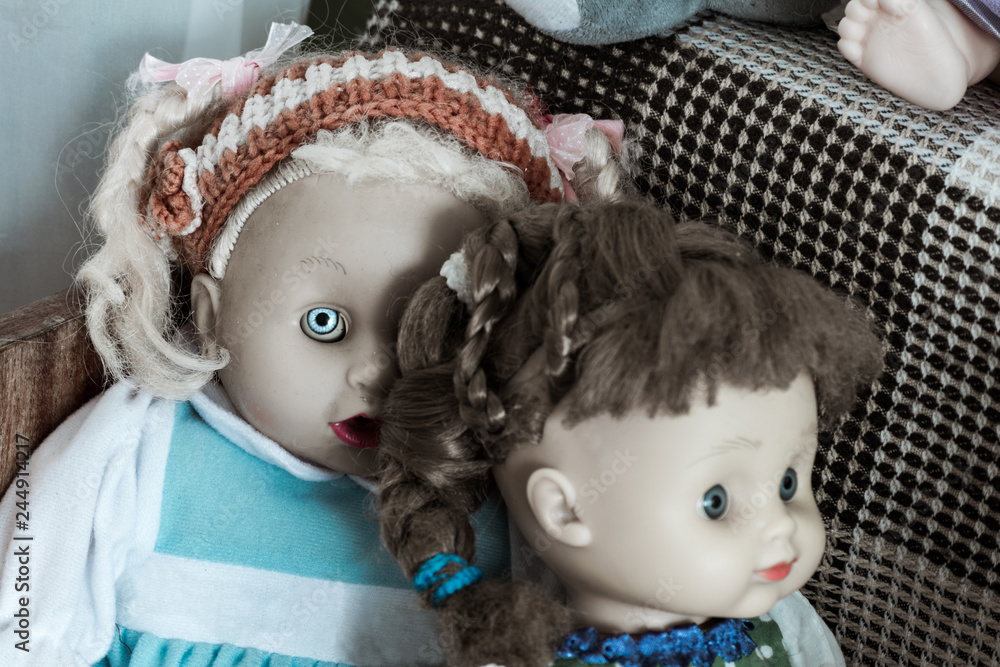 Creepy dolls. Demonic doll with one bright eye peeks out from behind the shoulder of another doll