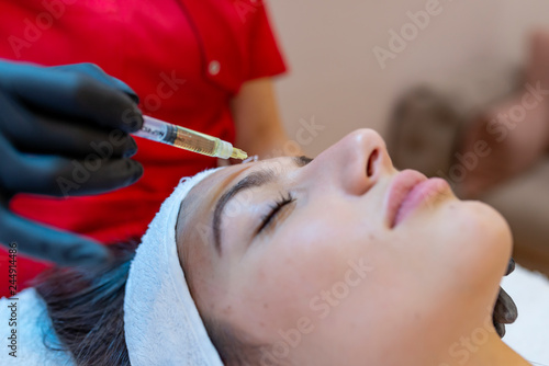 Hardware cosmetology, mesotherapy, portrait of young woman getting treatment of forehead zone