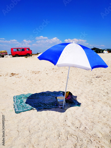 Beach colorful umbrella stith on the beach without anyone. Creates a shadow