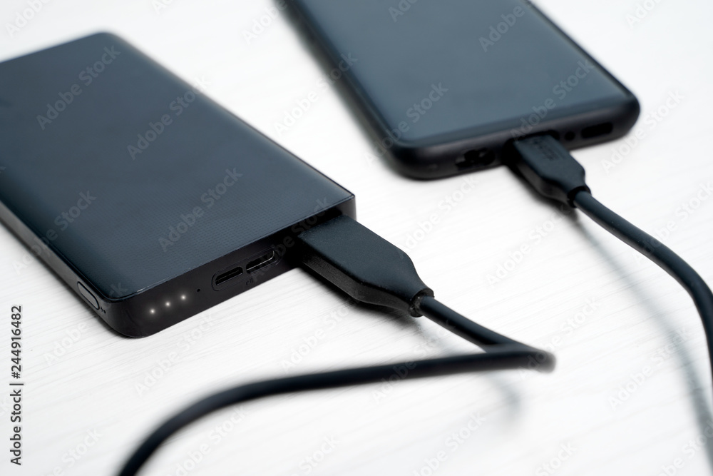 Photo of black powerbank with smartphone Photo of black powerbank with smartphone