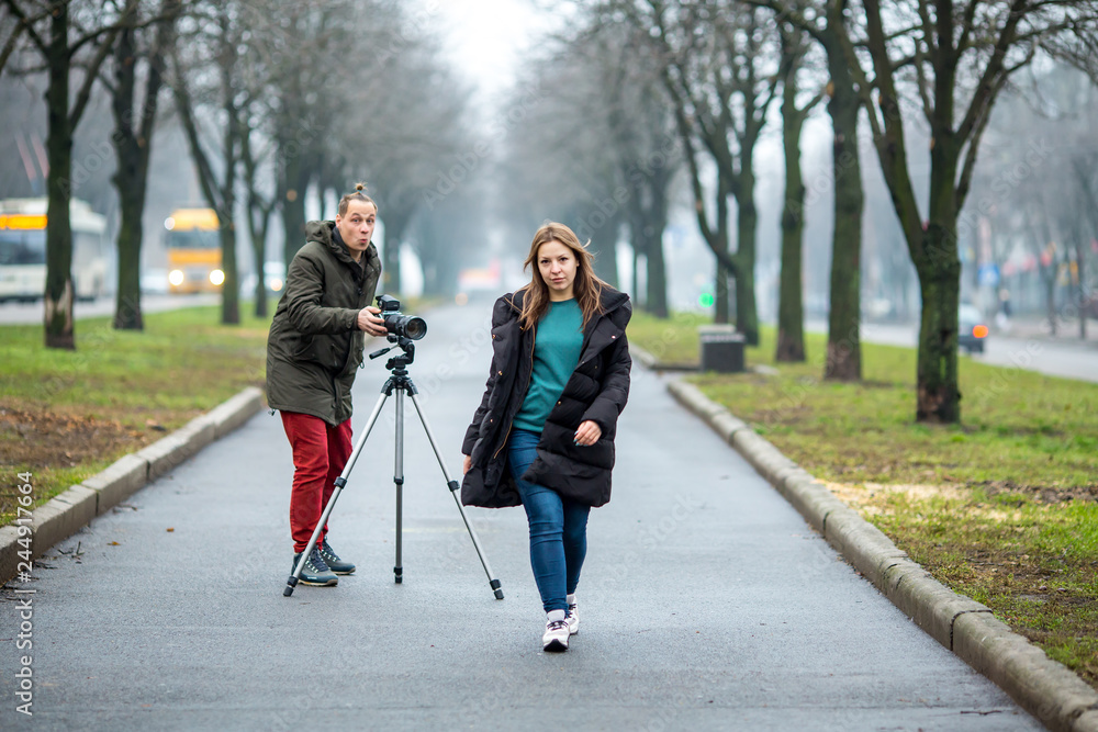 on the wolkway in town a guy takes a picture of a young girl of outdor