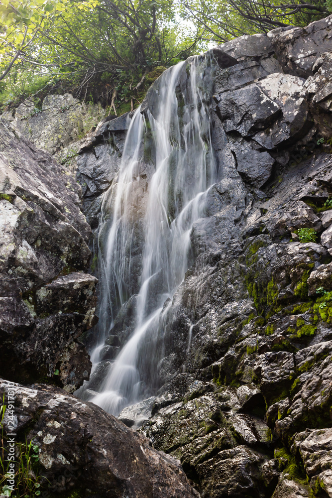 Naklejka premium Vertical waterfall in rocks. Mountain river in mountains.