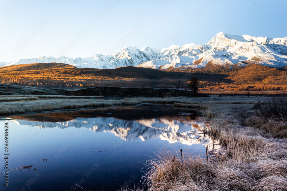Reflection of snowy mountain ridge in lake. Autumn in mountains. Travel Altai.