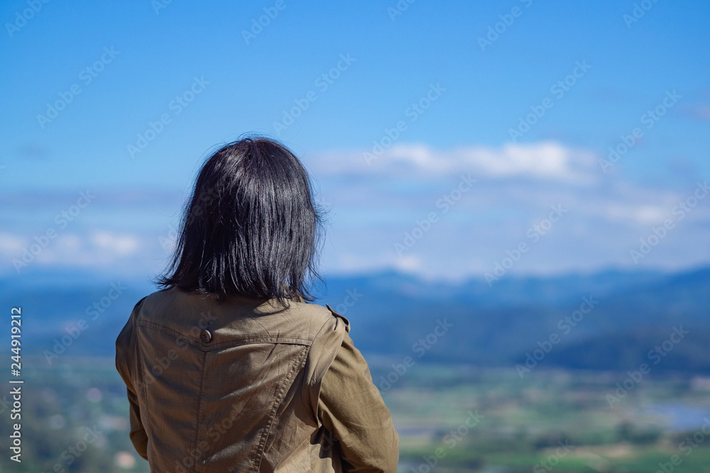 Back view of a woman person stands alone looking at mountains. Travel concept. Back View.