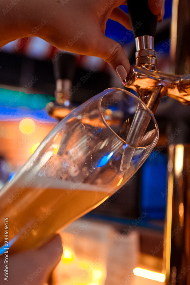 Fototapeta premium close-up of barman hand at beer tap pouring a draught lager beer