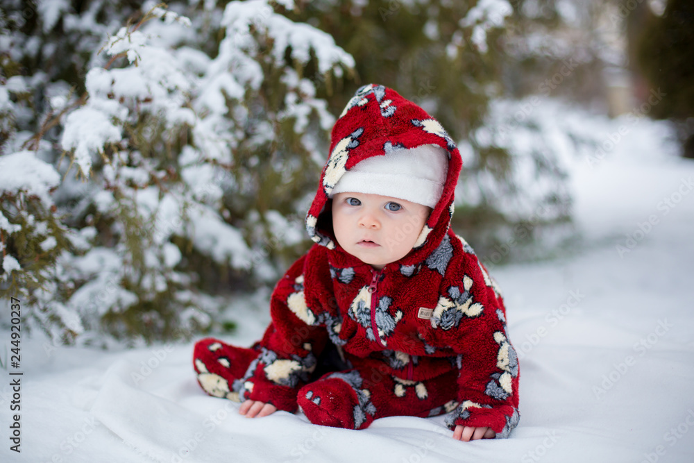 Little cute smiling baby boy, sitting outdoors in the snow Little cute smiling baby boy, sitting outdoors in the snow
