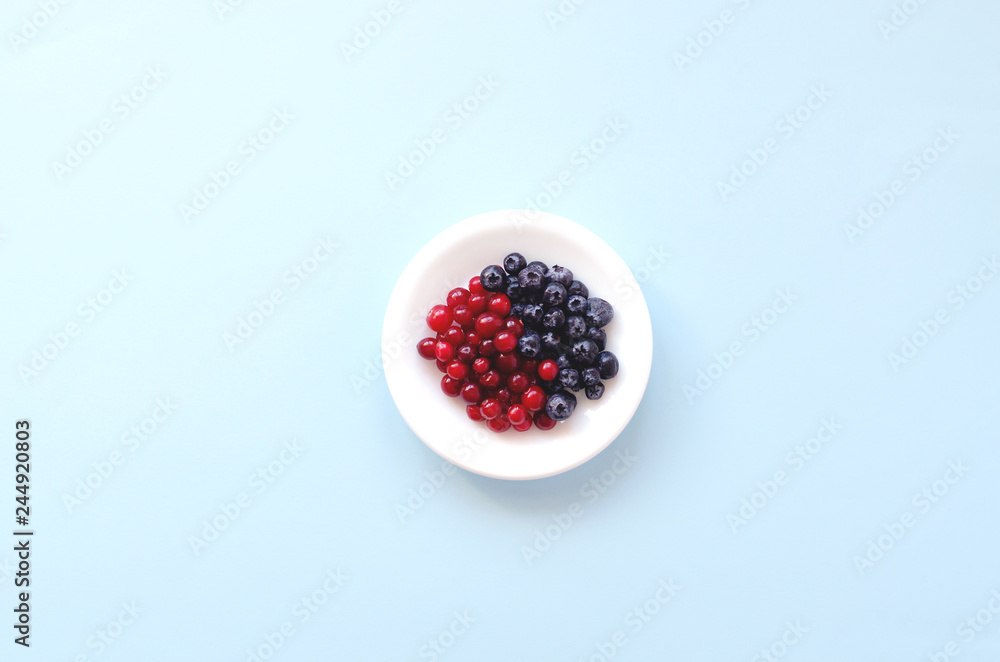White saucer with berries on a blue background. White saucer with berries on a blue background.
