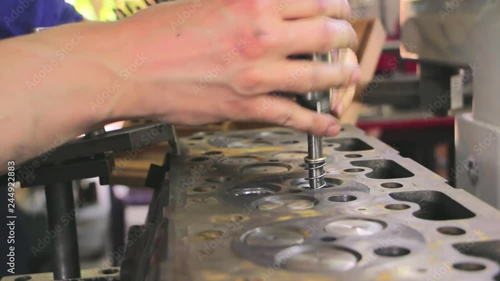 Cylinder head valves repair. Car engine repair in factory. Worker fixes