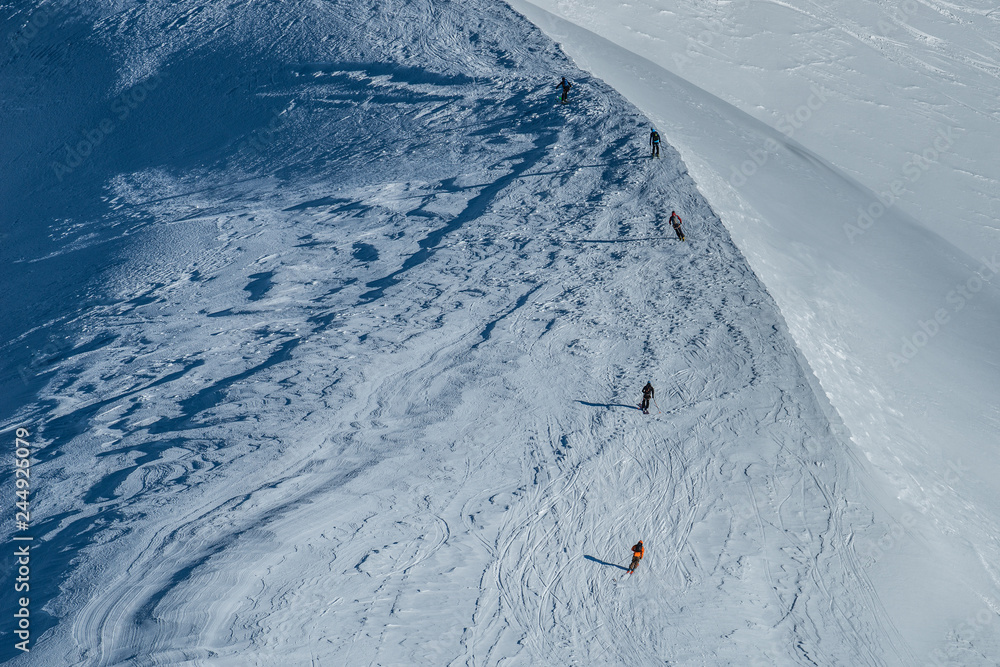Obraz premium Free ride skiers, skiing down steep slope, good background with white valley and mountains in french alps. Winter sport concept with adventure guys on mountain top hiking to start point.
