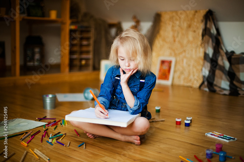 little girl lying on the floor and drawing with colored pencils photo