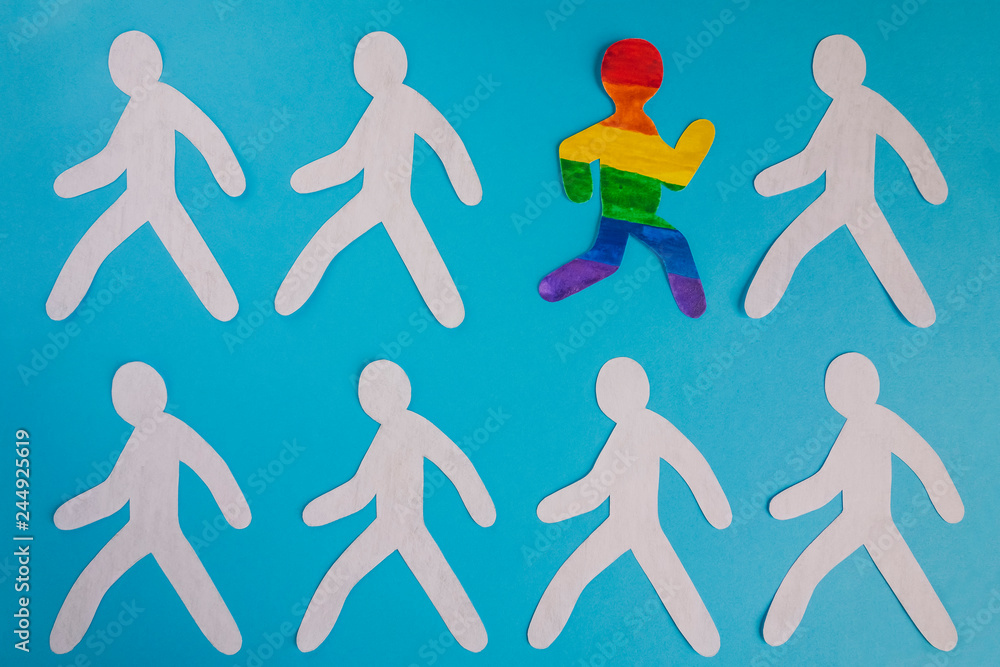 The paper man painted in the colors of the LGBT flag runs out of the gray mass. The paper man painted in the colors of the LGBT flag runs out of the gray mass.