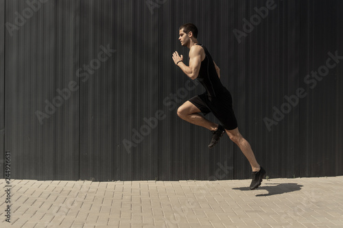 A side view shot of a fit young, athletic man jumping and running.