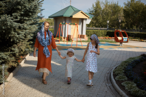 Russian Orthodox woman in a scarf goes along with her daughters, mother's day