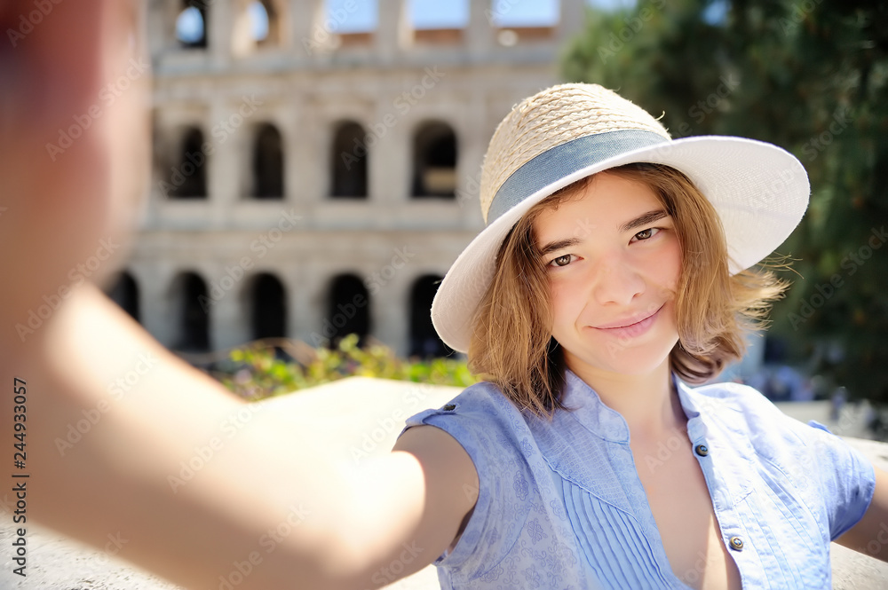 Young female traveler making selfie photo standing the Colosseum in Rome, Italy