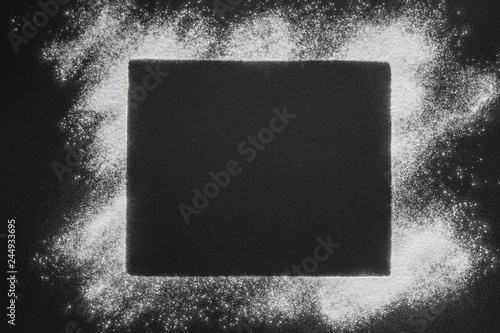 a white powder frame in sugar or flour optic on a black slate stone background