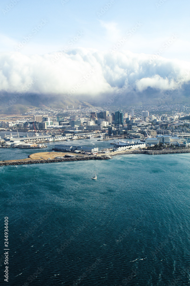 Aerial view of the skyline of cape town and table mountains with clouds hanging over it seen from a helicopter.