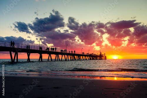 Glenelg pier with walking people silhouettes at sunset