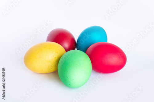 Multi-colored Easter eggs lie on a white background. Yellow, red, green and blue egg folded in the form of a flower.