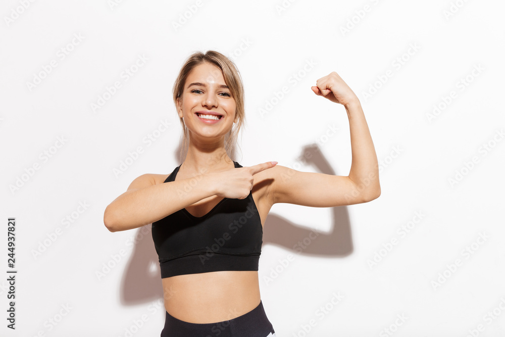 Beautiful young fitness woman isolated over white wall background showing biceps.
