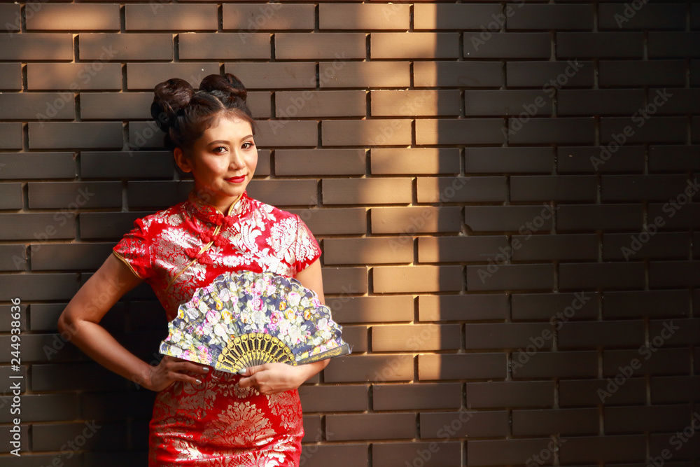 Chinese girl wearing beautiful dress Standing holding a blue against a black brick wall Chinese New Year Chinese girl wearing beautiful dress Standing holding a blue against a black brick wall Chinese New Year