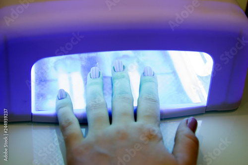 UV lamp gel polish manicure process in a beauty salon. Salon procedure. The master coats the client's nails with a varnish.