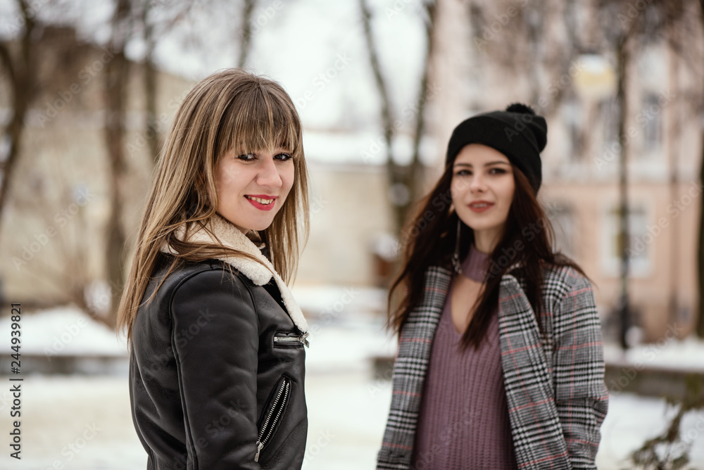 Obraz premium Two young trendy women in snowy winter park
