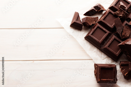 A large bar of black chocolate on a white wooden background with space for text.