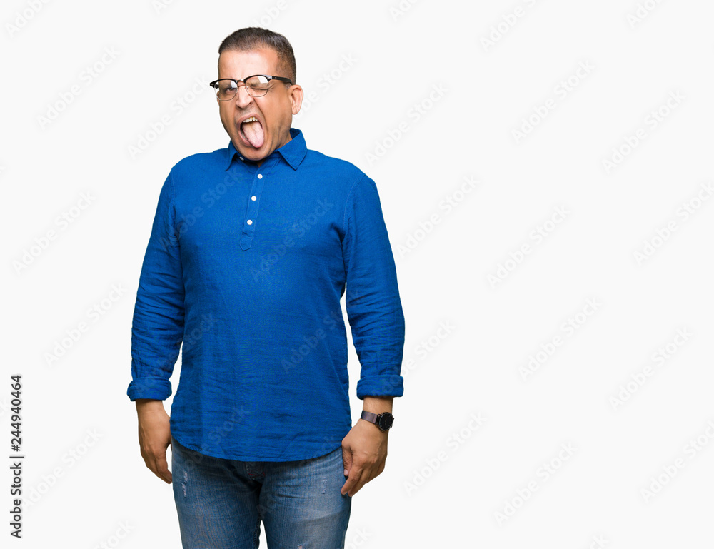 Fototapeta premium Middle age arab man wearing glasses over isolated background sticking tongue out happy with funny expression. Emotion concept.