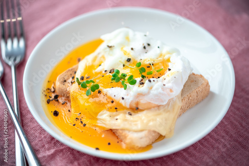 Breakfast, poached egg, bread and cheese on a white plate.
