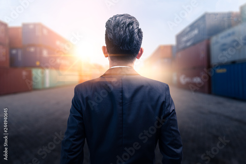 The abstract image of the engineer standing and looking up to the shipping container during sunrise. the concept of engineering, shipping, shipyard, business and transportations.