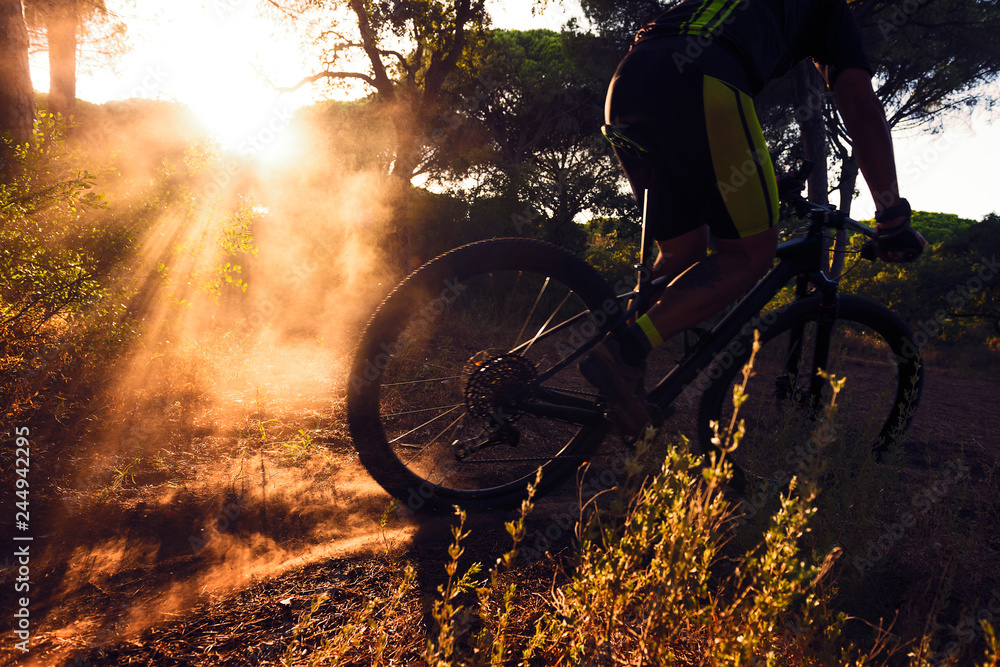Obraz premium cyclist skidding on mountain bike at sunset