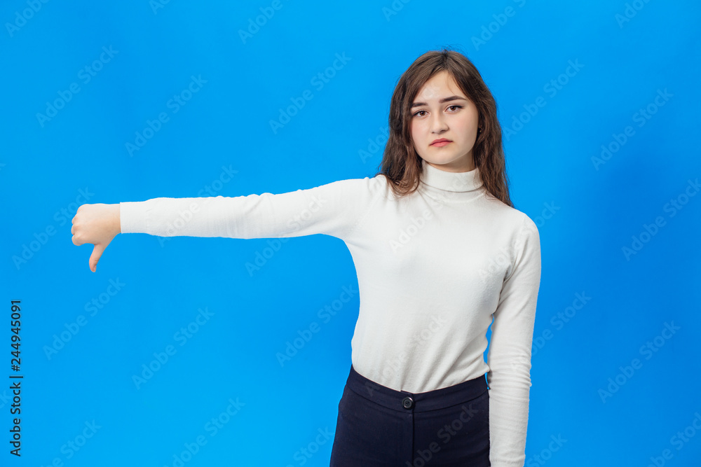 Happy young woman giving thumbs up. A girl on a blue background with smile Happy young woman giving thumbs up. A girl on a blue background with smile