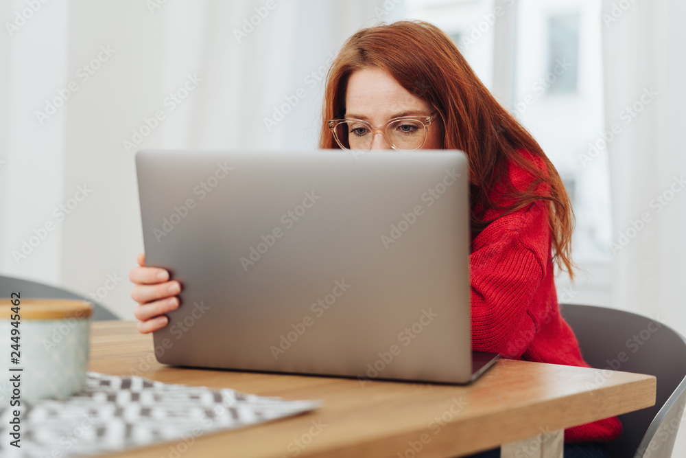Young woman wearing glasses working on a laptop Young woman wearing glasses working on a laptop