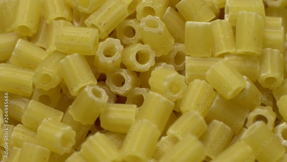 Raw macaroni in rotation. Ditalini lisci. Close up. Raw pasta, Italian cuisine concept. Raw macaroni in rotation. Ditalini lisci. Close up. Raw pasta, Italian cuisine concept.