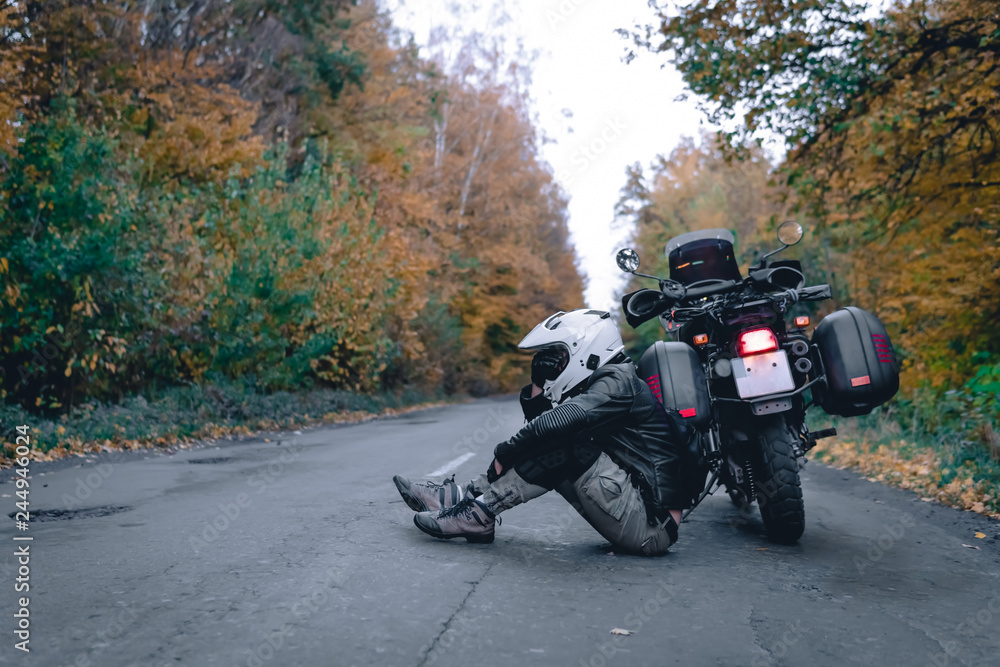 Biker man in leather jacket and black tourist motorcycle with side bags. wallpaper concept, enduro advetnture, space for text, autmn season, problems on the road accident Biker man in leather jacket and black tourist motorcycle with side bags. wallpaper concept, enduro advetnture, space for text, autmn season, problems on the road accident