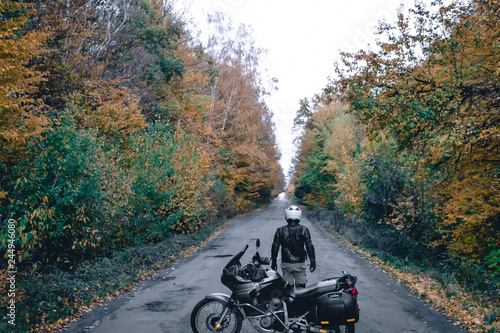 Biker man in leather jacket and black tourist motorcycle with side bags. wallpaper concept, enduro advetnture, space for text, autmn season