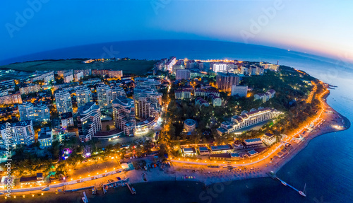 Gelendzhik embankment in the evening twilight from a bird's-eye view. The lights of the promenade are reflected in the smooth water of the Bay. Visible buildings of hotels and boarding houses. 