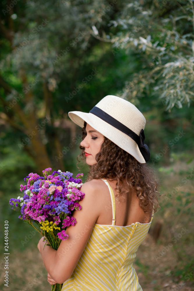 Fototapeta premium Woman with flowers in hands, wearing white hat.