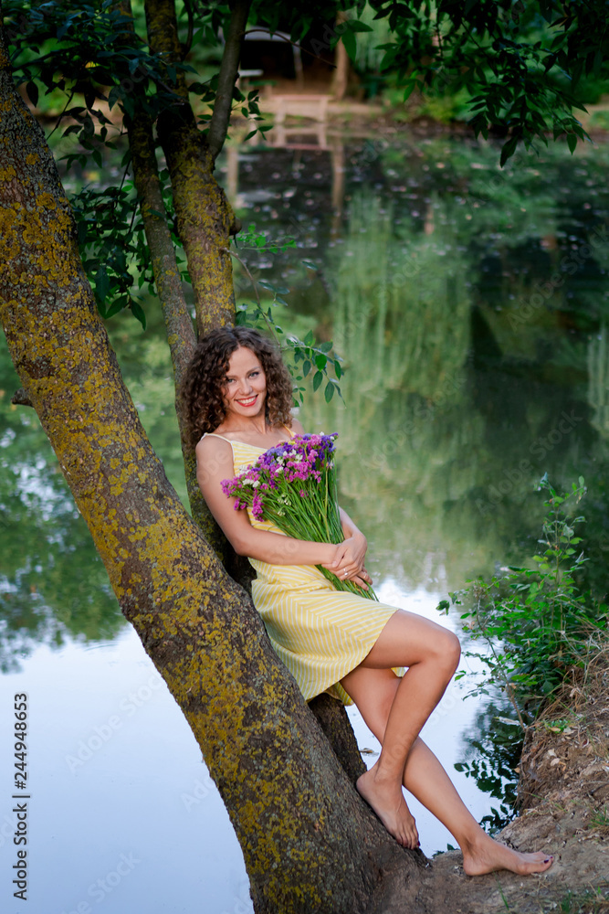 Woman with flowers in hands near lake Woman with flowers in hands near lake